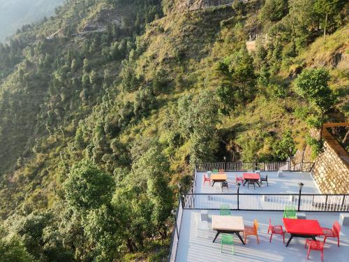 a group of tables and chairs on a viewing deck with a mountain at Bella Vista Hotel & Home Stay in Mussoorie