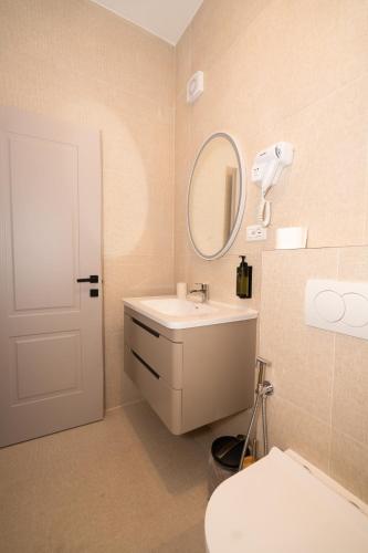 a bathroom with a sink and a mirror and a toilet at Hotel Dimora 1927 in Tirana