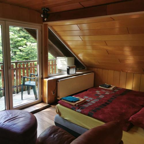 a bedroom with a bed in a room with a balcony at FEWO Radebeul Am Waldrand Spittelholz in Radebeul