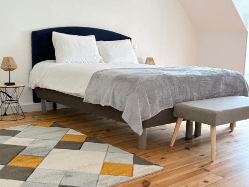 a bedroom with a large bed with a chair and a rug at Le calme dans 100M2 in Condé-sur-Sarthe