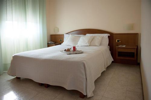 a bedroom with a large white bed with a candle on it at Hotel La Chiesaccia in Crespellano