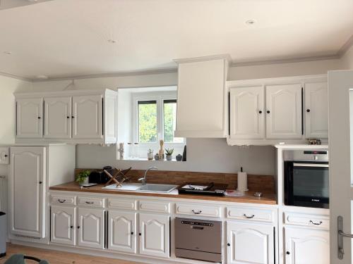 a white kitchen with white cabinets and a sink at Le calme dans 100M2 in Condé-sur-Sarthe