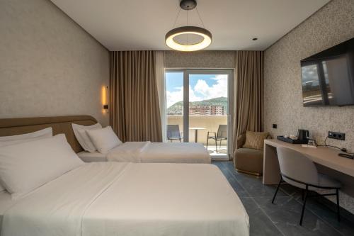 ein Hotelzimmer mit zwei Betten und einem Schreibtisch in der Unterkunft Hotel Mozart in Shkodra