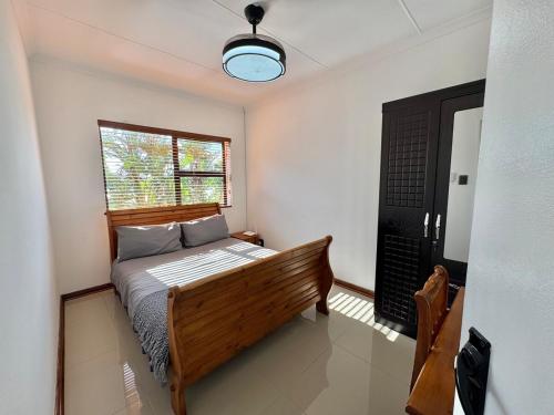 a bedroom with a wooden bed and a window at Sunesta Cottage in Gqeberha