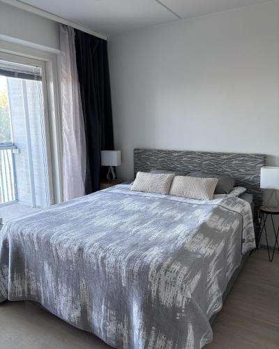 a bedroom with a large bed and a window at Modern studio next to Finnoo metro - Tuohi BossHomes in Espoo