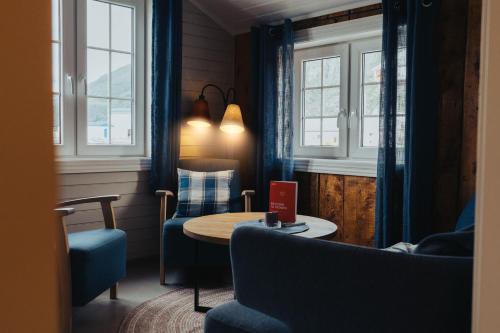 a living room with a table and chairs and windows at Svinøya Rorbuer in Svolvær
