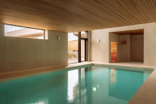 a swimming pool in a house with blue water at Elements Terschelling by Dutchen in Midsland