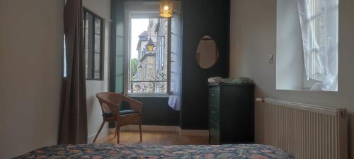 a bedroom with a bed and a chair and a window at Le Cocon - Vue sur le Port de DINAN - Parking privé in Lanvallay