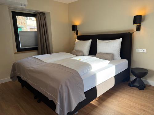 ein Schlafzimmer mit einem großen Bett mit weißer Bettwäsche und einem Fenster in der Unterkunft Hotel am Hafen in Cochem
