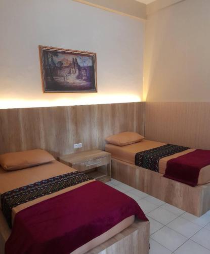 ein Hotelzimmer mit zwei Betten und einem Bild an der Wand in der Unterkunft Hotel Pesaban in Tjakranegara