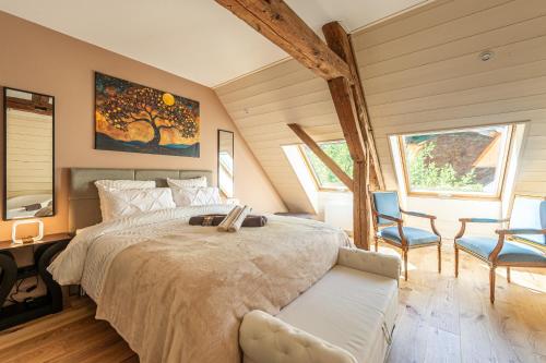 a bedroom with a large bed and two chairs at Le Moulin de mes garçons in Alby