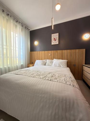 a bedroom with a large white bed and a window at Elite Apartments Masaka in Kigali