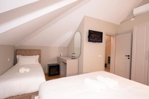 a bedroom with two beds and a tv on the wall at Hotel Dimora 1927 in Tirana