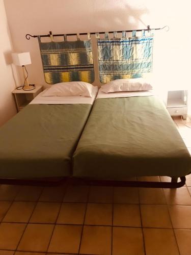 a bed in a room with a green bedspread at Lagrange Vacances Résidence du Golf in Saint-Cyprien