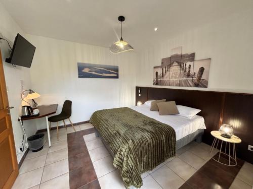 a bedroom with a bed and a desk and a tv at Logis Hôtel L'Oliveraie in Cognac