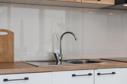 a kitchen with a stainless steel sink and white cabinets at Le Bleu Apartment Pool & Beach by PikHost in Lezhë