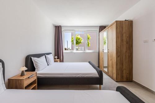 a bedroom with a bed and a chair and a window at Le Bleu Apartment Pool & Beach by PikHost in Lezhë