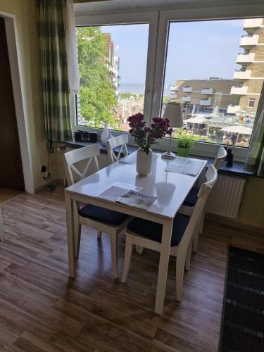 a dining room table with a vase of flowers on it at Haus Schildt, FeWo 2 in Duhnen