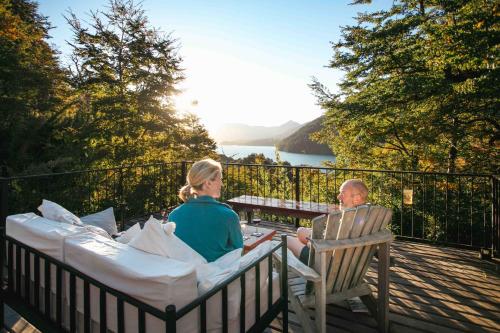 a man and a woman sitting at a table on a balcony at Hermoso Eco Lodge in San Martín de los Andes