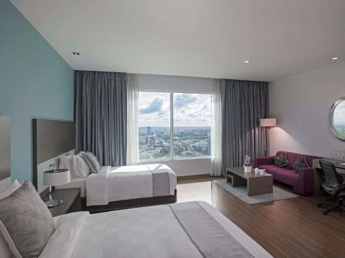 a hotel room with a bed and a large window at Pullman Kuching in Kuching