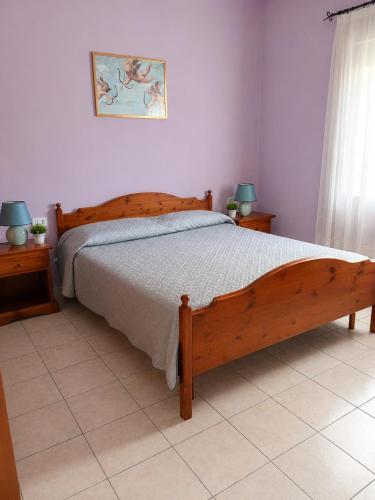a bedroom with a wooden bed and two night stands at Zia Peppina in Tertenìa
