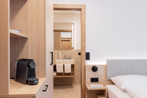 ein kleines Badezimmer mit Bett und Waschbecken in der Unterkunft odilum - Self-Check-in-Hotel in Mondsee