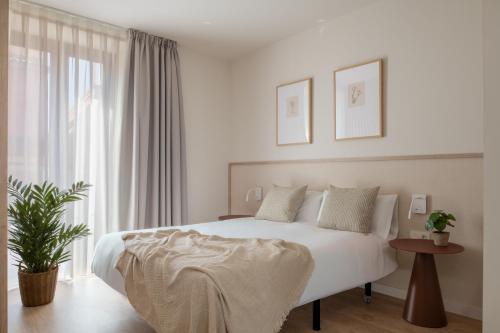 a white bedroom with a large bed and a window at Líbere Seville Triana in Seville