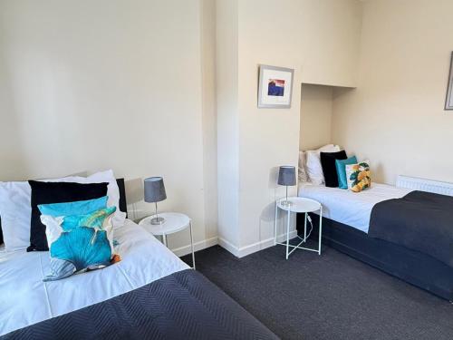 a bedroom with two beds and two tables in it at SPACIOUS 3 BEDROOM HOUSE WITH FREE STREET PARKING and WIFI IDEAL FOR CONTRACTORS by NORTH WEST ACCOMMODATION in Saint Helens