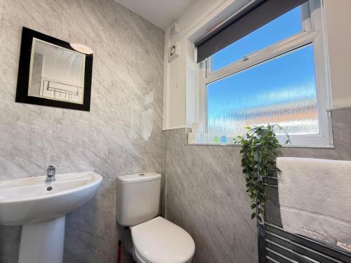 a bathroom with a toilet and a sink and a window at SPACIOUS 3 BEDROOM HOUSE WITH FREE STREET PARKING and WIFI IDEAL FOR CONTRACTORS by NORTH WEST ACCOMMODATION in Saint Helens