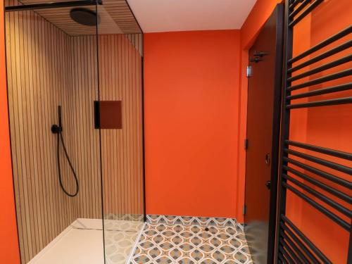 a shower with orange walls and a glass door at The Cozie Sow in Yeovil