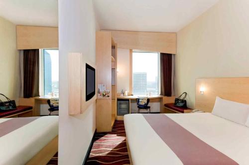 a hotel room with two beds and a television at ibis Sharq in Kuwait