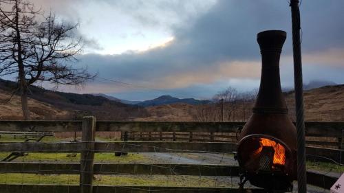 a wood fired stove is next to a fence at Garrison Farm with Hot Tub in Inversnaid