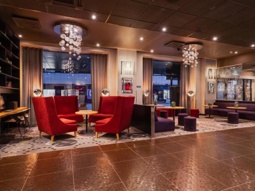 a restaurant with red chairs and tables in a room at Park Inn by Radisson Central Tallinn in Tallinn