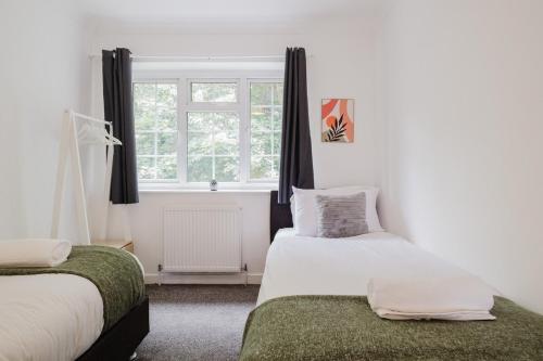 a bedroom with two beds and a window at Spacious 4-Bed Home with Free Parking in Northampton