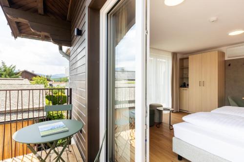 ein Zimmer mit Balkon, mit Bett und Tisch in der Unterkunft odilum - Self-Check-in-Hotel in Mondsee