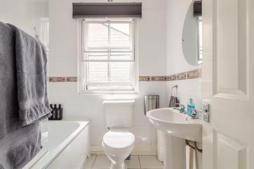 a white bathroom with a toilet and a sink at Entire 1 Bed Central Flat - St Albans in St. Albans