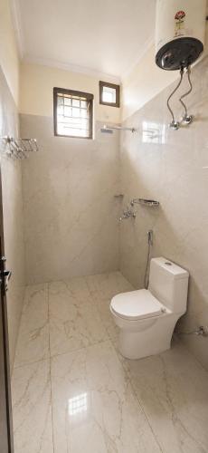 a white bathroom with a toilet and a window at Sukoon stays Bhimtal 3 bed in Bhīm Tāl