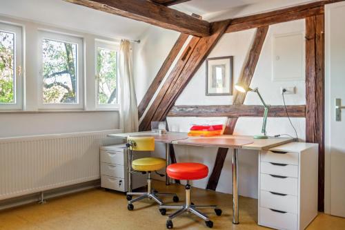 an attic office with a desk and two chairs at Alte Schmiede Ellrichshausen 1 in Satteldorf
