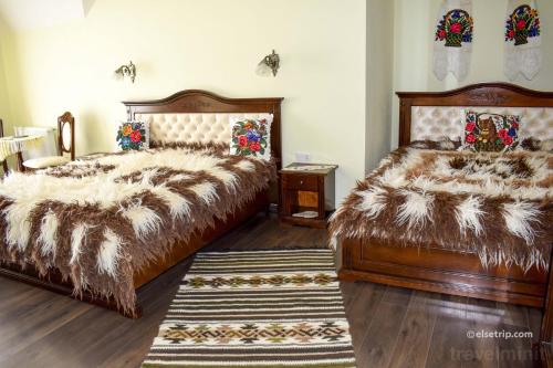 a bedroom with two beds and a rug at Pensiunea Baias in Bîrsana
