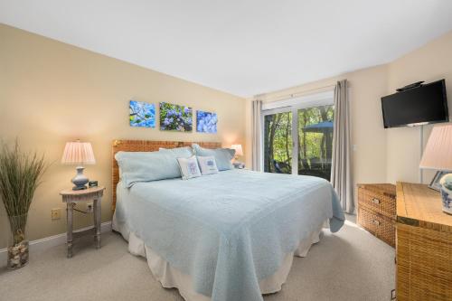 a bedroom with a bed with a blue comforter and a window at Sea Spark - Cape Escape with Pool Access in Mashpee