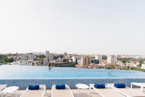 a swimming pool on the roof of a building with chairs at Jupiter Porto Hotel - Rooftop & Spa in Porto