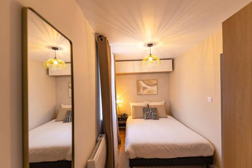 a mirror in a room with two beds in it at L'échappée de l'Arbalète in Autun