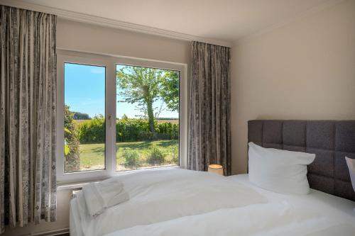 a bedroom with a bed and a large window at Boddenweite 3 in Born