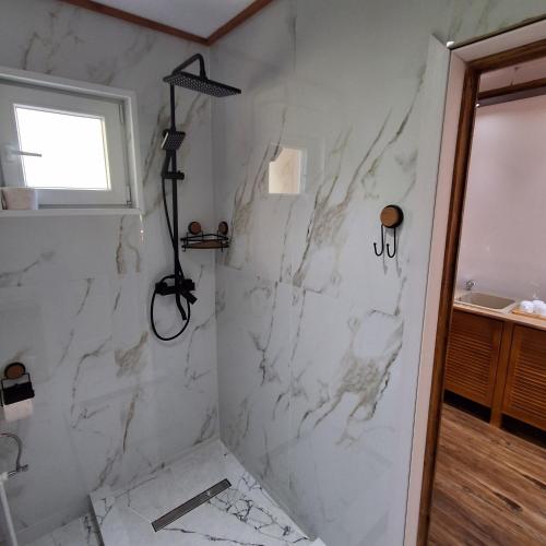 ein Badezimmer mit Dusche aus weißem Marmor in der Unterkunft Silent A-FRAME in Brăteşti