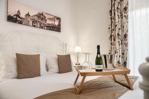 a white bed with a bottle of wine on a table at Aulino House in Catania
