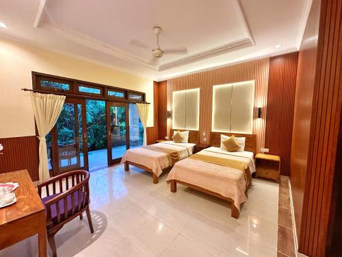 a hotel room with two beds and a table at Frangipani Bungalow in Ubud