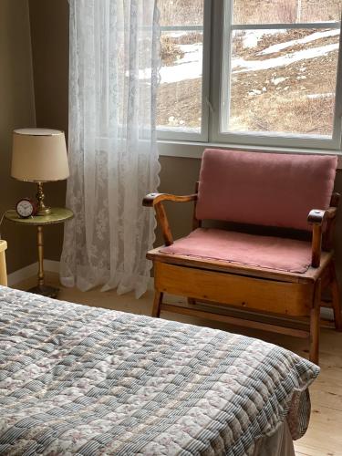a bedroom with a chair in front of a window at Snertingdal ysteri in Gjøvik