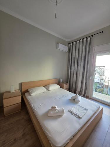 a bedroom with a bed with white sheets and a window at Center Twin Apartments - 2 in Chios