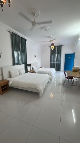 two beds in a large room with white floors and windows at Salem Fish Guest House in Al Ḩadd