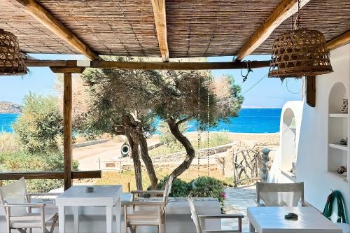 a restaurant with white tables and chairs and a view of the ocean at Baba Houlakia in Houlakia